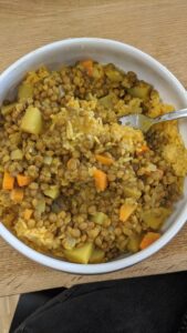 A bowl of yellow curry with lentils, potatoes and carrots